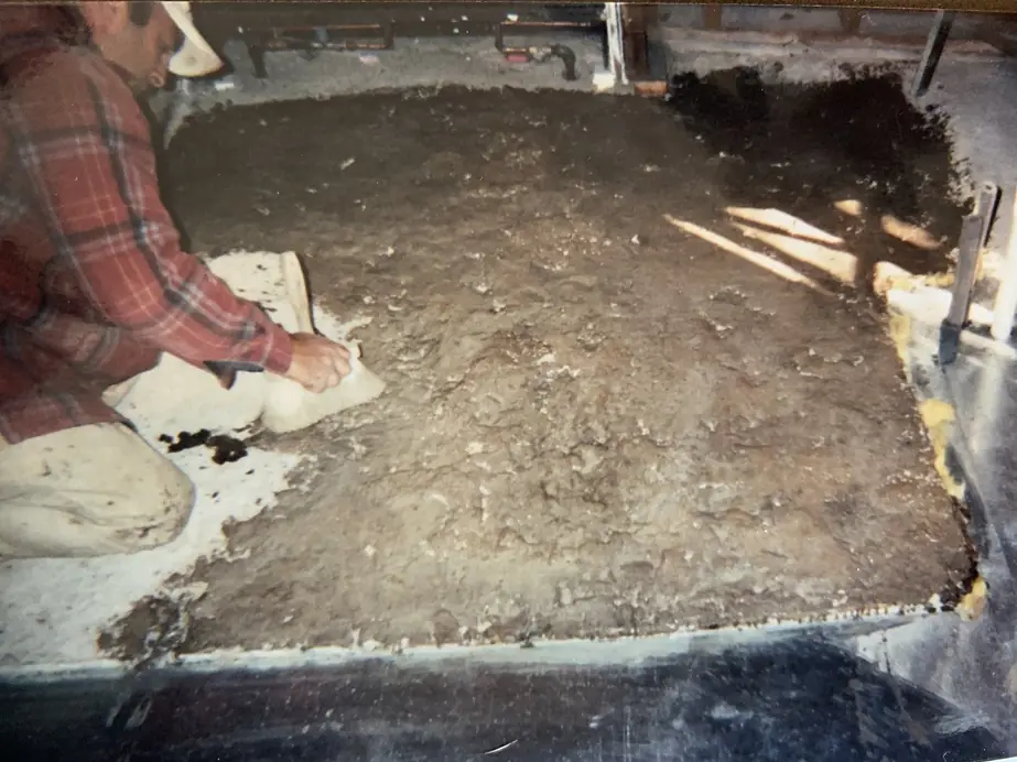 A Carl Johanson & Son worker kneeling on a board, hand-finishing a freshly poured interior concrete slab